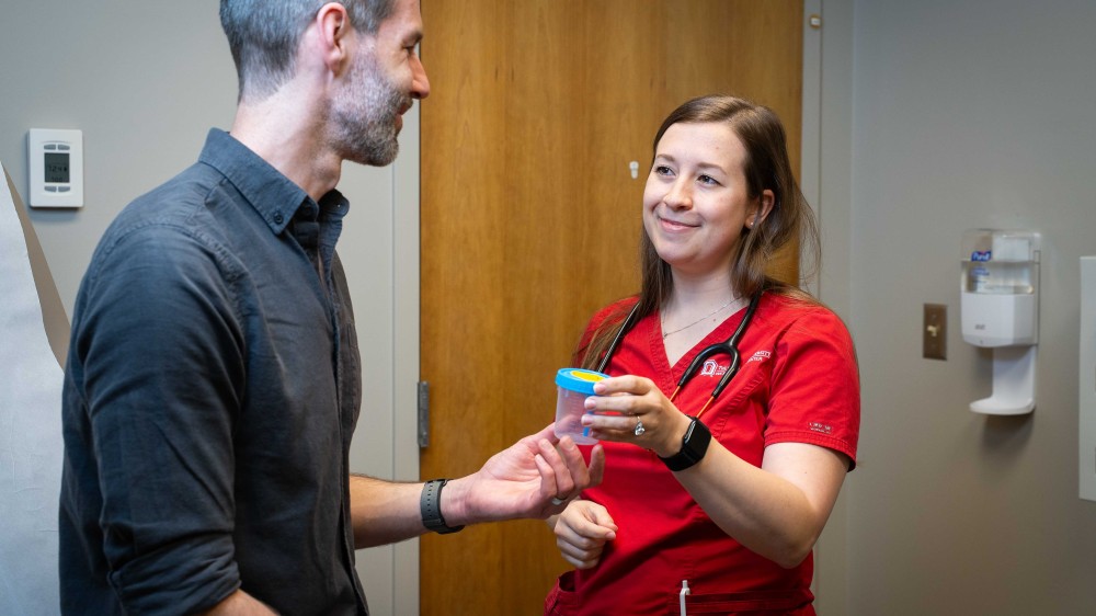 health care provider handing patient a specimen cup